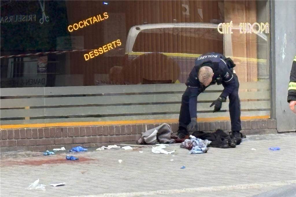 Waffeneinsatz bei Streit in Herten: Zwei Männer schwer verletzt: Spekulation um Axt-Angriff Ein Polizist durchsucht Wäschestücke auf dem Boden vor dem Café in Herten.