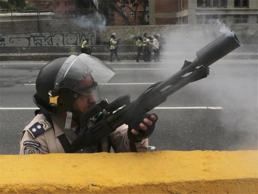 Appell an Venezuelas Militär: "Nicht mit Titanic untergehen" Ein Polizist feuert Tränengas in Richtung protestierender Demonstranten. Foto: Fernando Llano