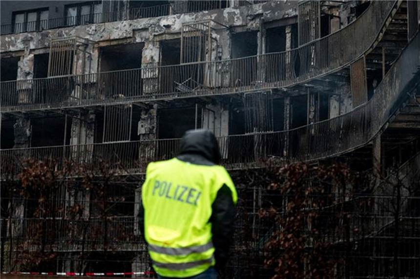 Brand in Essen: Polizei schickt neuen Roboterhund in die Brandruine Ein Polizist steht vor der runtergebrannten Fassade des Wohnkomplexes in Essen.