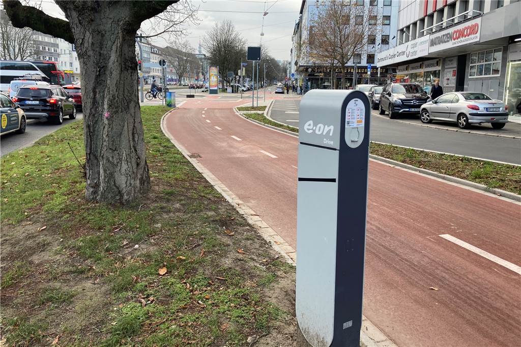 Kurioses Bild am Wall: E-Ladesäule steht unerreichbar auf Grünfläche Ein Radweg trennt die E-Ladesäule am Schwanenwall von der angrenzenden Straße.