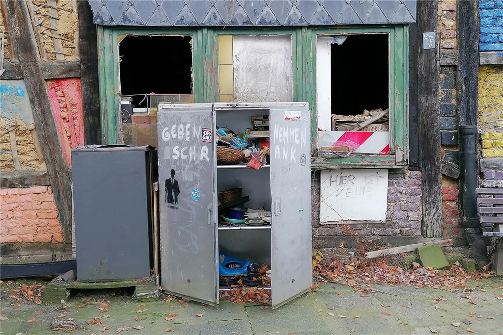 Sechs Monate nach Großbrand: Früheres „Schiefereck“ kein Denkmal mehr Ein Stahlschrank mit Büchern, Geschirr und anderen Gegenständen zum Tauschen auf dem Bürgersteig vor der Brandruine.