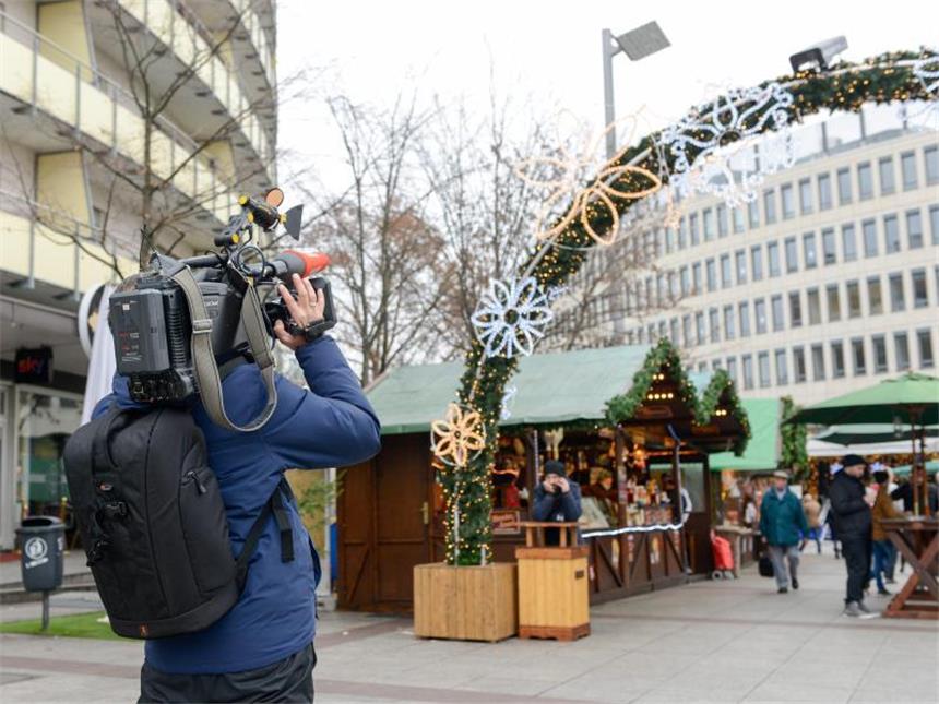 Ludwigshafener Bombenfund lässt Fragen offen Ein Reporter filmt den Weihnachtsmarkt in Ludwigshafen. In Rathaus-Nähe war ein Rucksack mit einem Sprengsatz gefunden worden. Foto: Martin H. Hartmann