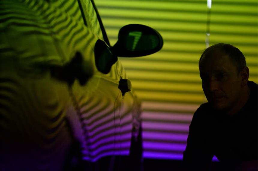 Hagelschäden am Auto jetzt schnell melden Ein Sachverständiger der Allianz AG untersucht ein Auto in einem Hagelscanner auf Hagelschäden.