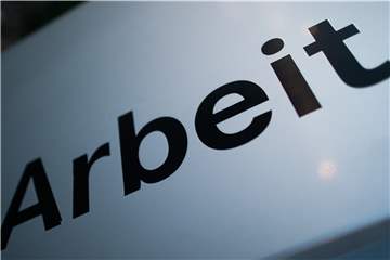 Ein Schild steht mit Schriftzug „Arbeit“ steht vor einem Standort der Agentur für Arbeit.