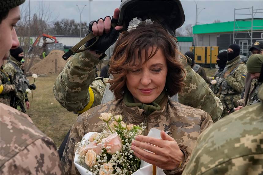 Putins Krieg in der Ukraine: Fünf Geschichten, die Mut machen Ein Soldat hält einen Helm als Hochzeitskrone während der Hochzeitszeremonie für die Mitglieder der ukrainischen Territorialen Verteidigungskräfte Lesia Ivashchenko und Valerii Fylymonov, an einem Kontrollpunkt in Kiew.