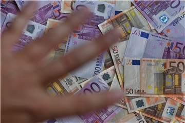 Hand, die nach einer großen Menge 500-Euro-Scheinen und 50-Euro-Scheinen greift.