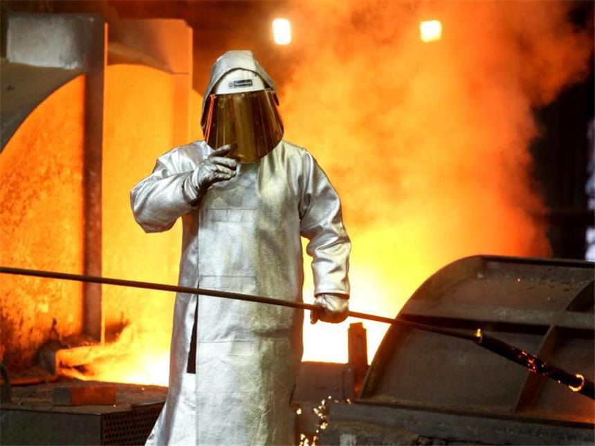 Ein Stahlarbeiter prüft an einem Hochofen bei ThyssenKrupp in Duisburg die Stahlqualität nach dem Abstich. Foto: Roland Weihrauch