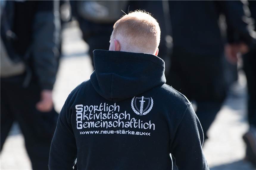 Deutsche Rechtsextreme mit Waffenerlaubnis in die Ukraine gereist Ein Teilnehmer einer Kundgebung von Neonazis trägt einen Pullover mit der Aufschrift „Sportlich Aktivistisch Gemeinschaftlich“.