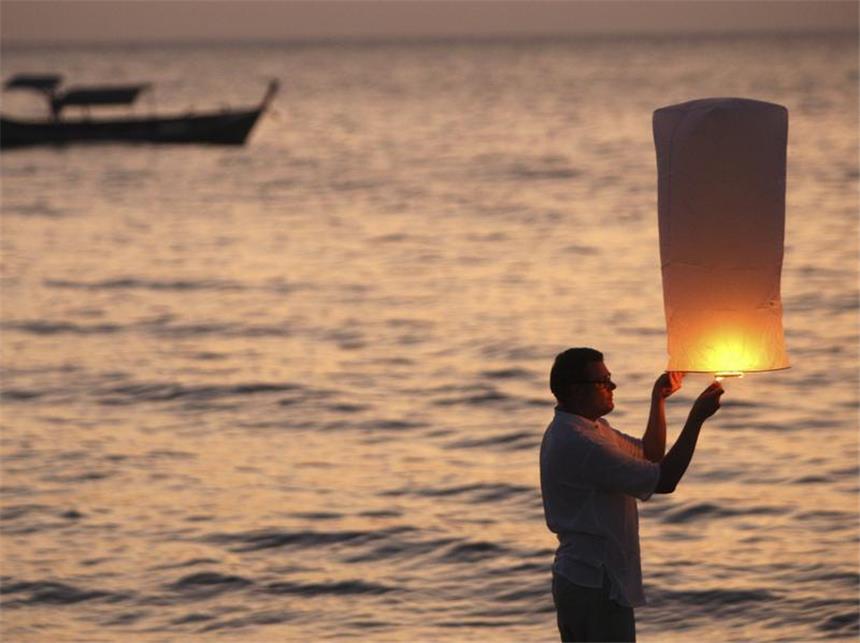 Thailand und Indonesien gedenken der Tsunami-Opfer Ein Tourist aus Finnland entzündet am Bangniang Beach eine Laterne in Erinnerung an seinen guten Freund, der bei dem Tsunami 2004 ums Leben kam. Foto: Rungoj Yongrit/Archiv