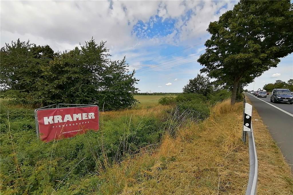 Industriegebiet „Dicker Dören“ beschlossen: Groppenbrucher wollen klagen Transparent des Unternehmens Kramer am Rande des Areals. Rechts Autos auf der Mengeder Straße in Waltrop.