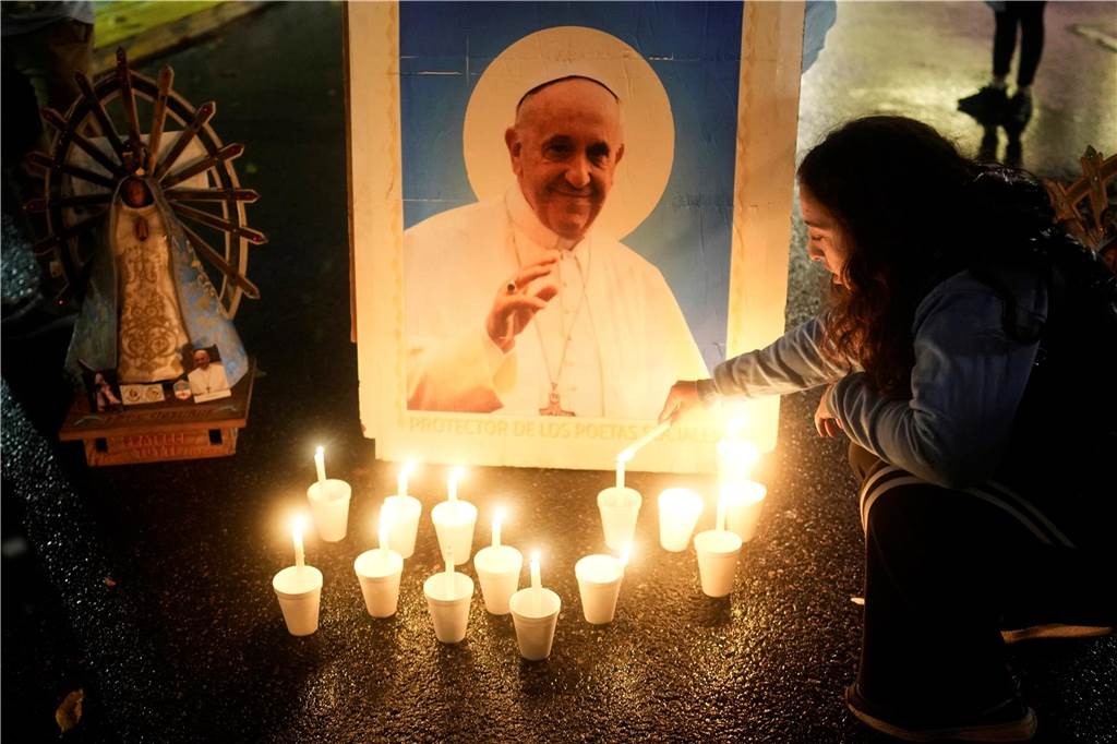 Jetzt live: Trauerfeier für Papst Franziskus beginnt: Sarg vor Altar aufgestellt Ein Trauernder zündet eine Kerze vor einem Bild des verstorbenen Papstes Franziskus vor der Kathedrale in Buenos Aires an, während sein Begräbnis in Rom stattfindet.