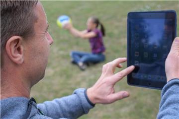 Ein Vater schaut auf sein Tablet, während die Tochter spielt. Foto: Patrick Pleul