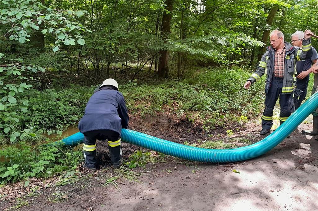 Umgestürzter Anhänger mit Güllefass ruft Feuerwehr Werne auf den Plan Feuerwehrleute reinigen mit einem Schlauch den Weg.