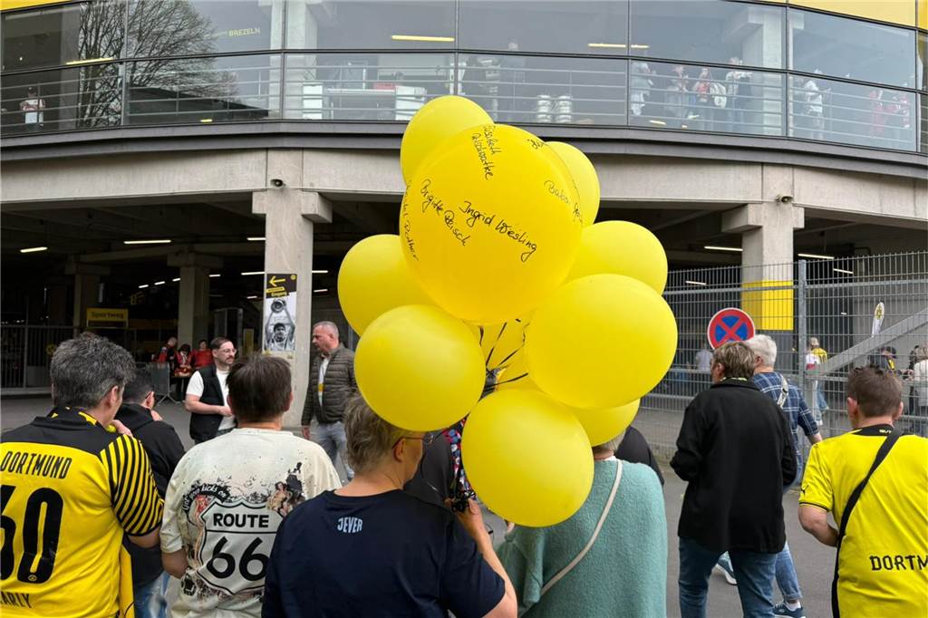 Eine Frau trägt mehrere gelbe Luftballons