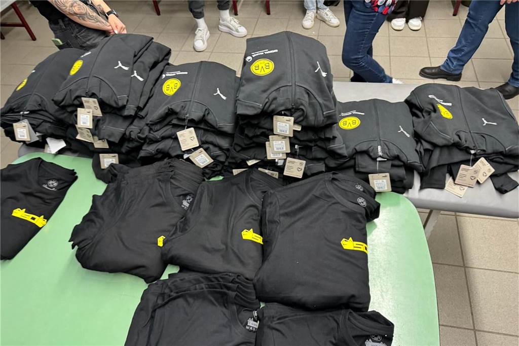 Auf einem Tisch liegen Jacken mit BVB-Logo