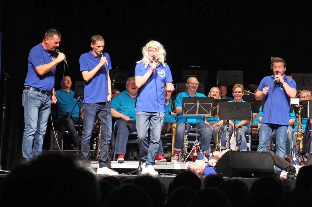Bläsercorps Werne und 6-Pipes verbreiten Humor und Musikalität Die Musiker stehen auf der Bühne und singen.