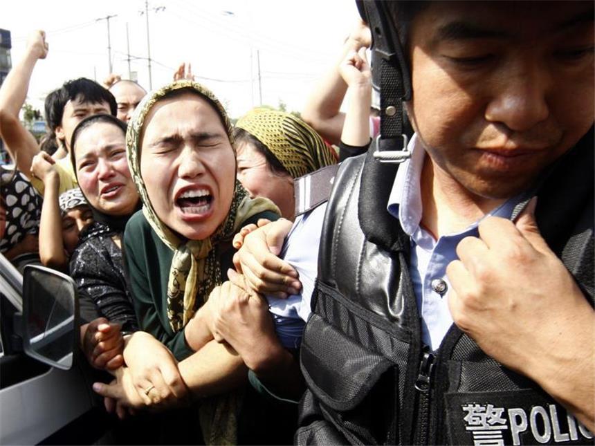 31 Tote bei Anschlag in Chinas Unruheregion Xinjiang Eine Angehörige der uigurischen Minderheit rangelt bei einer Demonstration in Ürümqi mit einem Polizisten. Foto: Oliver Weiken/Archiv