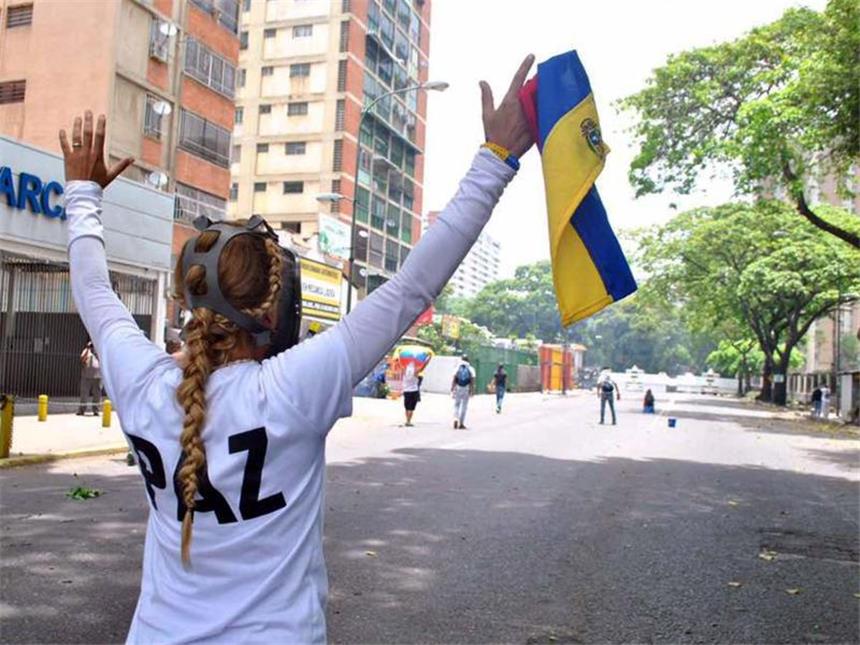 Appell an Venezuelas Militär: "Nicht mit Titanic untergehen" Eine Demonstrantin mit Gasmaske die Landesflagge in den Händen. Der blutige Machtkampf im Land mit den größten Ölreserven eskaliert. Foto: José Cohen