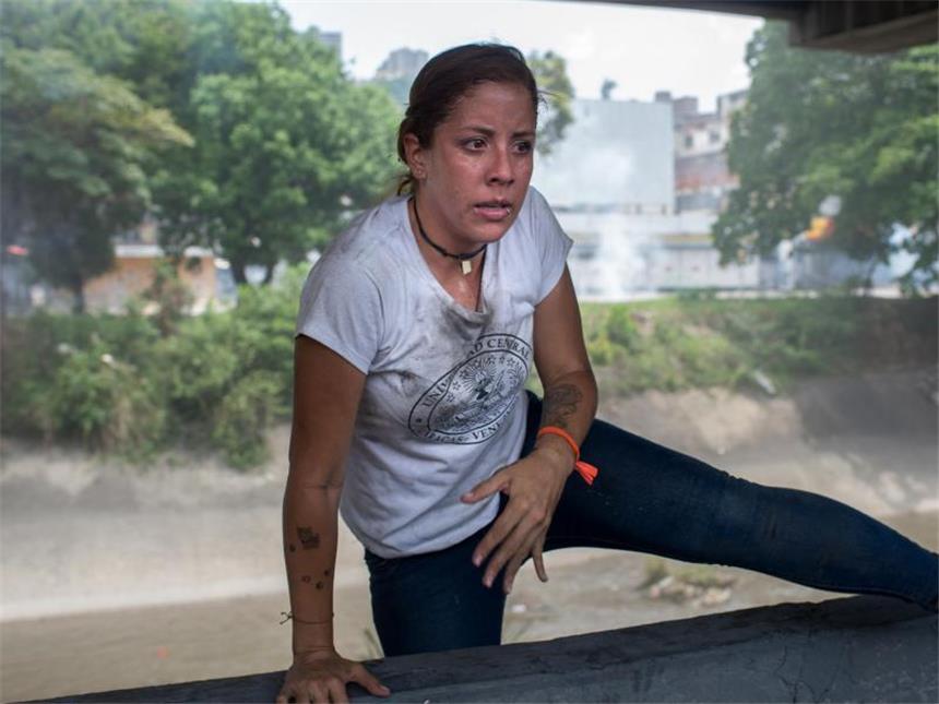 Lage in Venezuela eskaliert: Drei Tote Eine Demonstrantin springt über eine Mauer. Foto: Manaure Quintero