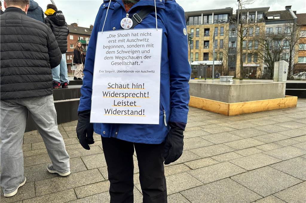 Eine Person hat ein Schild auf ihrem Bauch. Das Schild ruft auf Widerstand zu leisten. 