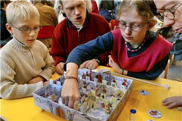 Eine Familie spielt auf der Essener Spielemesse mit einem Brettspiel. Foto: R. Weihrauch/Archiv