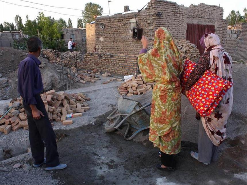 Mehr als 200 Tote nach schweren Erdbeben im Iran Eine Familie steht vor den Trümmern ihres Hauses. Foto: Stringer