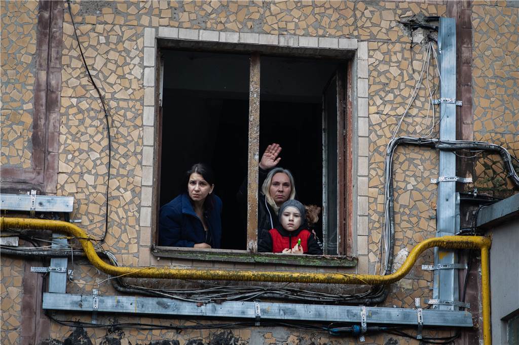 Schwerter Pastor hilft Flüchtlingen: „Selbst im größten Leid gibt es Hoffnung“ Eine Familie winkt einem Feuerwehrmann nach einem russischen Raketenangriff aus ihrem Fenster zu.