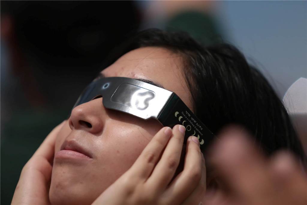 Sonnenfinsternis: Gerd Wüst gibt Tipps und warnt eindringlich Eine Frau beobachtet mithilfe einer Schutzbrille eine partielle Sonnenfinsternis.