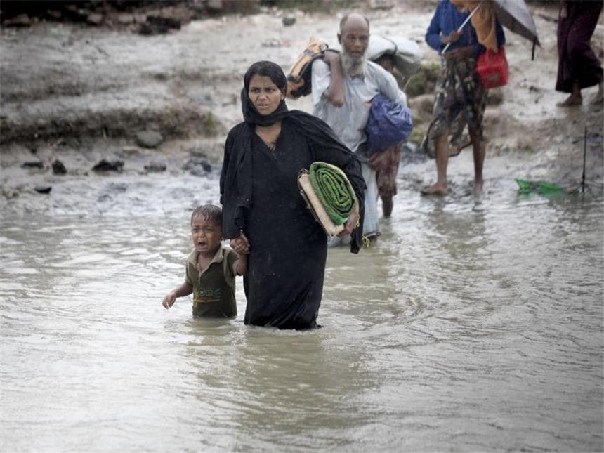 Eine Frau der muslimischen Minderheit der Rohingya durchquert in Bangladesch mit ihrem Sohn einen Kanal. Foto: Km Asad/ZUMA Wire