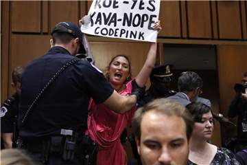 Eine Frau protestiert bei der Anhörung und wird von Polizisten aus dem Gebäude geführt. Foto: Jacquelyn Martin/AP