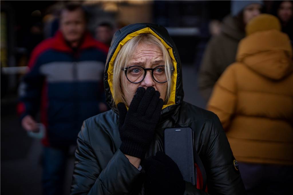 Ukrainer auf der Flucht: Es war einmal ihr Land Eine Frau reagiert vor einem Supermarkt im Zentrum der ukrainischen Hauptstadt auf Sirenen, die neue Angriffe ankündigen. In Kiew und anderen ukrainischen Städten sollen nach dem Angriff durch Russland zentrale Verteilungspunkte für Lebensmittel eingerichtet werden