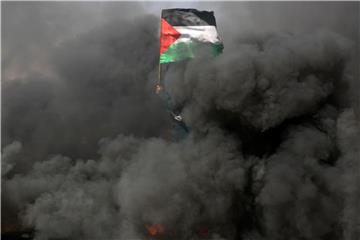 Eine Frau schwenkt bei Protesten an der Grenze zu Israel im Gazastreifen inmitten von Rauchschwaden eine palästinensische Flagge. Foto: Ashraf Amra/APA Images via ZUMA Wire