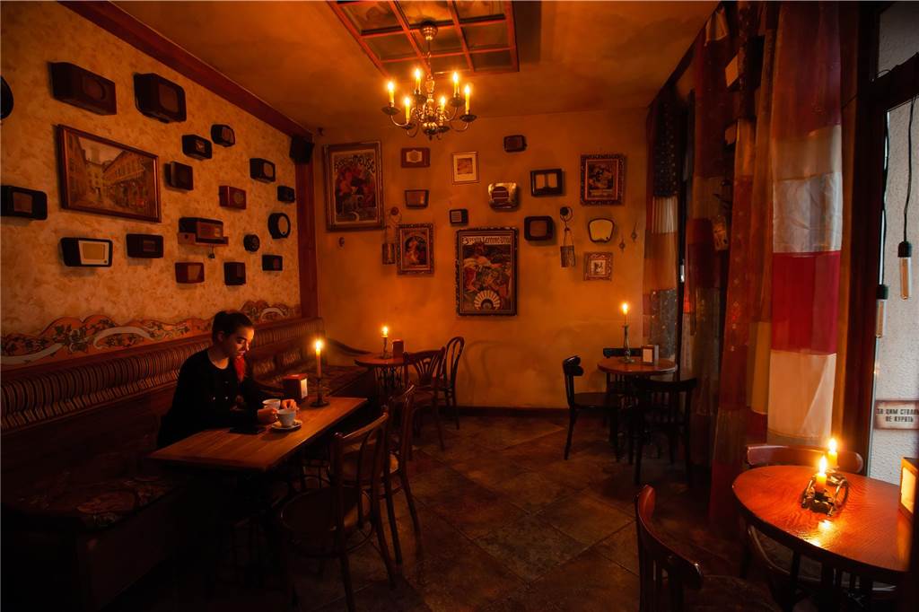 Ein Jahr Krieg in der Ukraine: Diese Orte und Geschehnisse sind besonders in Erinnerung geblieben Eine Frau sitzt in einem mit Kerzen beleuchteten Restaurant, während eines Stromausfalles.