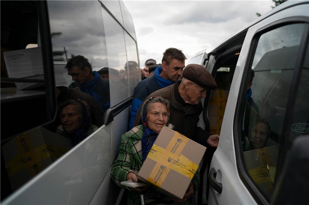 Ein Jahr Krieg in der Ukraine: Diese Orte und Geschehnisse sind besonders in Erinnerung geblieben Eine Frau trägt ein Hilfspaket in der durch ukrainische Streitkräfte zurückeroberten Stadt.