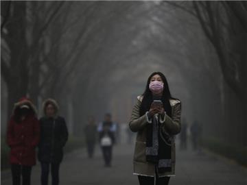 Eine Frau trägt in einem Park in Peking einen Mundschutz gegen den Smog. Der von der Regierung wegen der Smog-Alarmstufe "Rot" verhängte Produktionsstopp ist von vielen Fabriken ignoriert worden. Foto: How Hwee Young/Archiv
