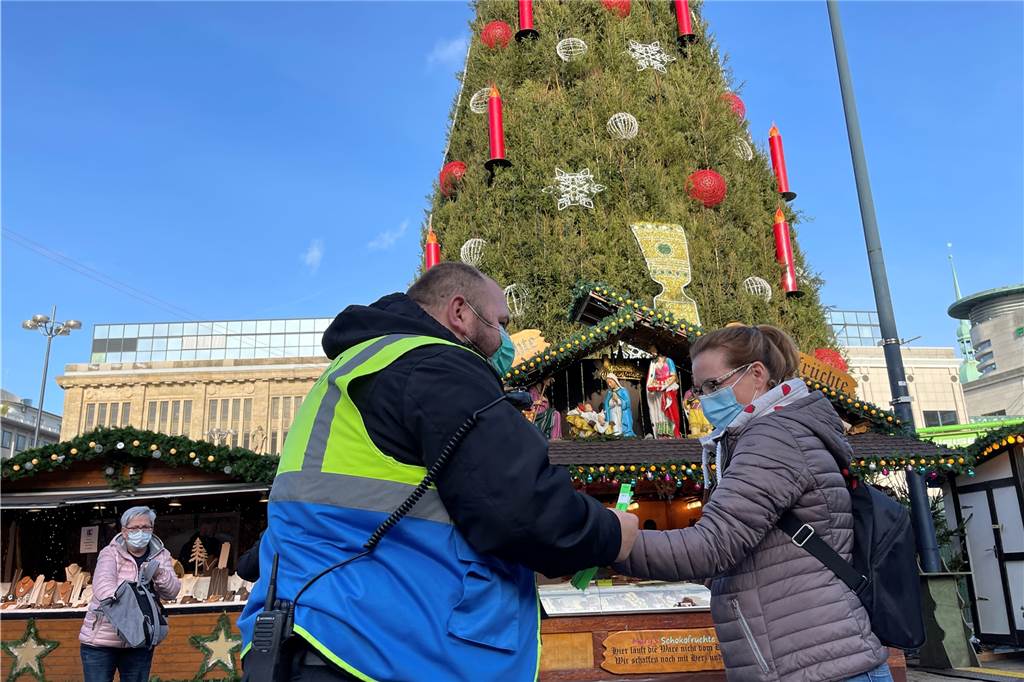 Dortmunder Weihnachtsmarkt mit 2G-Regel: Wie streng wird kontrolliert? Eine Frau wird auf dem Weihnachtsmarkt kontrolliert und bekommt ein Bändchen - es gilt 2G.