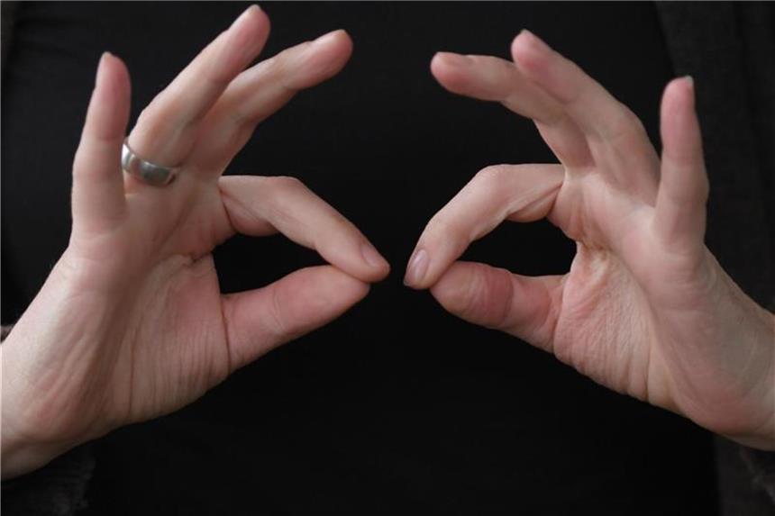 Eine Gebärdendolmetscherin zeigt mit ihren Fingern das Wort "regelmäßig" in Gebärdensprache. Foto: Arne Dedert