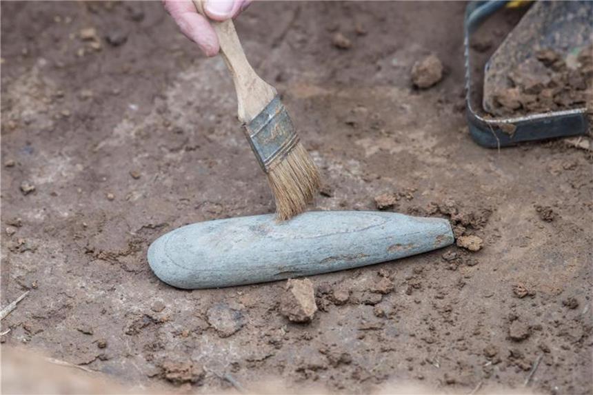 Grabungen in Warburg: So lebten Westfalen vor 7000 Jahren Eine Grabungstechnikerin reinigt eine Beil-Spitze aus Stein. Foto: Guido Kirchner