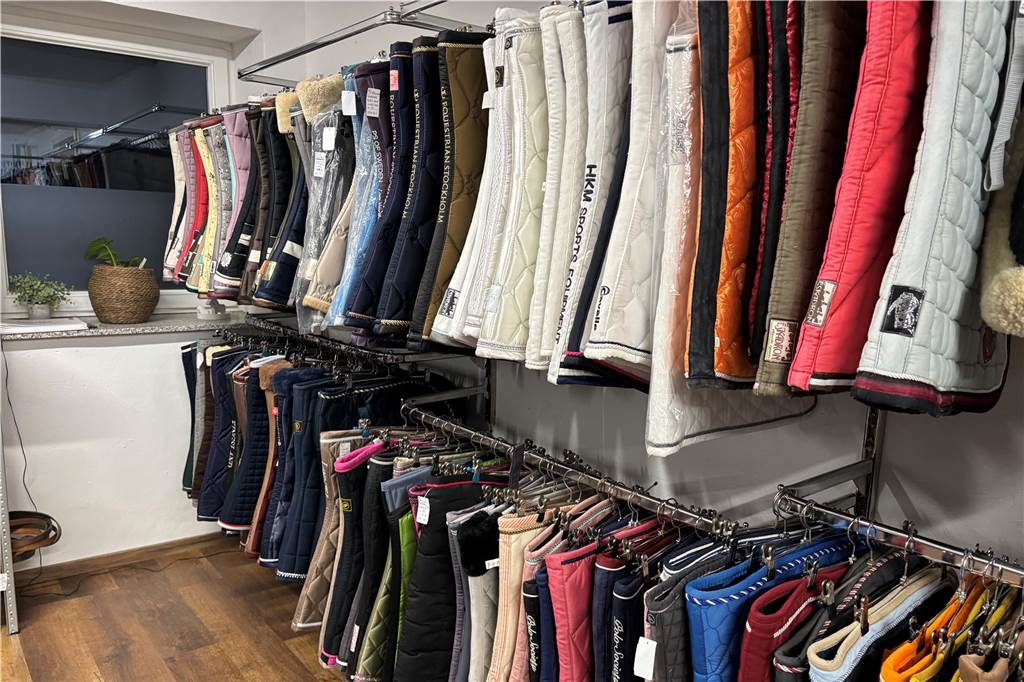 Mareen Robers betreibt einen Second Hand Shop für Reisportartikel Schabracken hängen an einem Ständer
