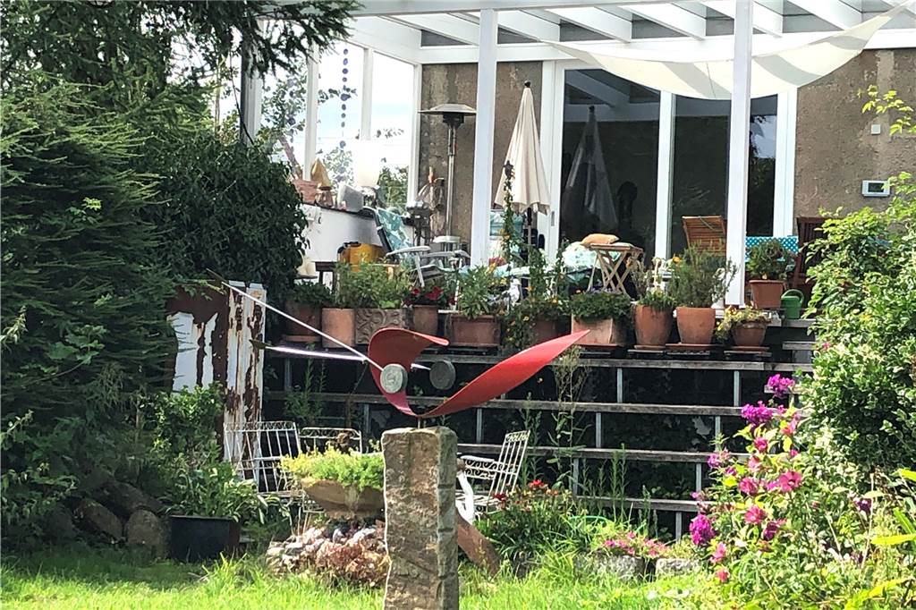 Das Haus am Halterner See: „Ich fühle mich wie ein Sonntagskind“ Eine Holztreppe führt hinauf auf die Terrasse und ins Haus. Überall sieht der Gast Kunst und herrliches Grün.