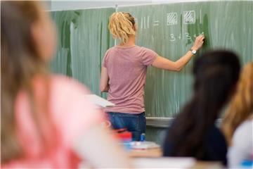 Eine junge Lehrerin schreibt an eine Schultafel. Foto: Julian Stratenschulte