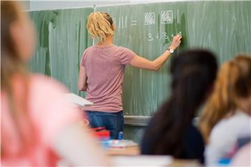 Eine Lehrerin schreibt an eine Schultafel. Foto: Julian Stratenschulte/Archiv