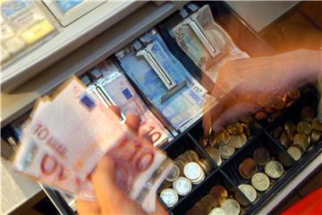 Eine Person entnimmt Geld aus einer Registrierkasse. Foto: Peter Kneffel/Archiv