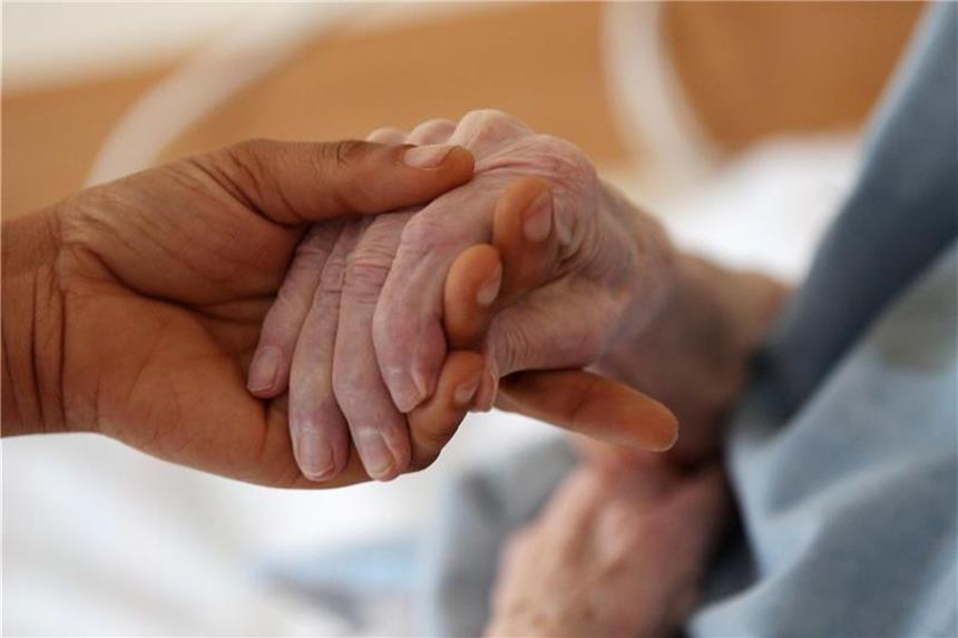 Eine Pflegerin hält die Hand einer Patientin. Foto: Oliver Berg/Archiv