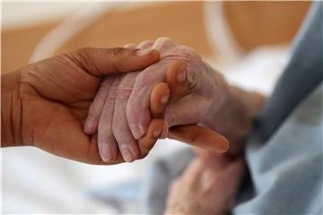 Eine Pflegerin hält die Hand einer Patientin. Foto: Oliver Berg/Archiv