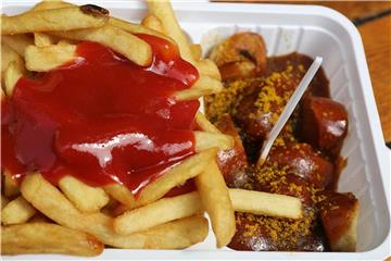 Eine Portion Currywurst Pommes mit Ketchup steht auf dem Tisch. Foto: Oliver Berg
