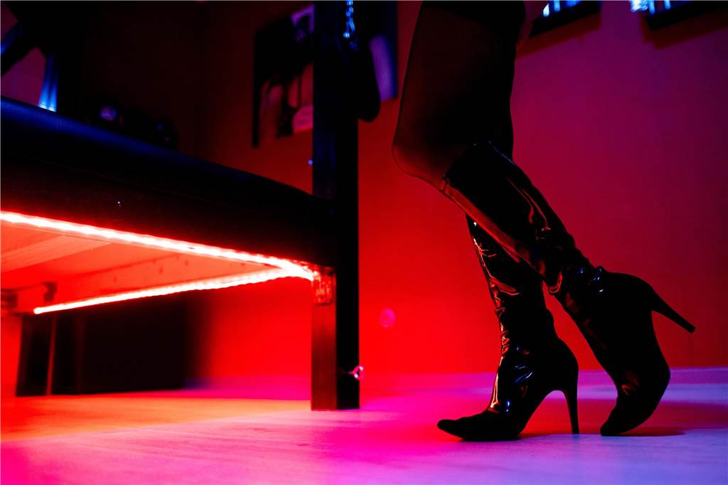Eine Prostituierte steht vor der roten Beleuchtung unter einem Bett in einem Studio. In Holzwickede wurde eine 32 Jahre alte Sexarbeiterin von einem Dortmunder angegriffen. 