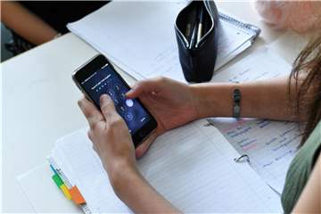 Eine Schülerin hält im Unterricht ein Handy in den Händen. Foto: Jens Kalaene/Illustration