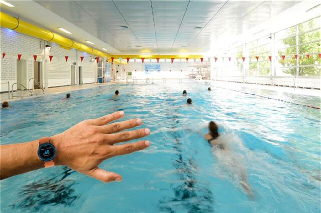 Das Überwachungssystem im Stadtbad geht in den Testbetrieb Jemand schaut im Schwimmbad auf seine Smartwatch.