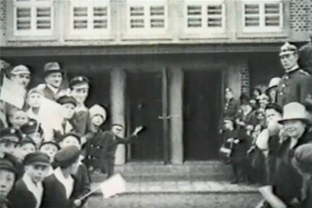 Menschen versammeln sich vor dem Werner Bahnhof im Jahr 1928.